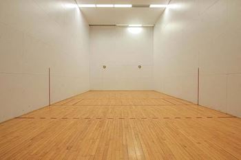 a white room with a wooden floor and a racquetball court